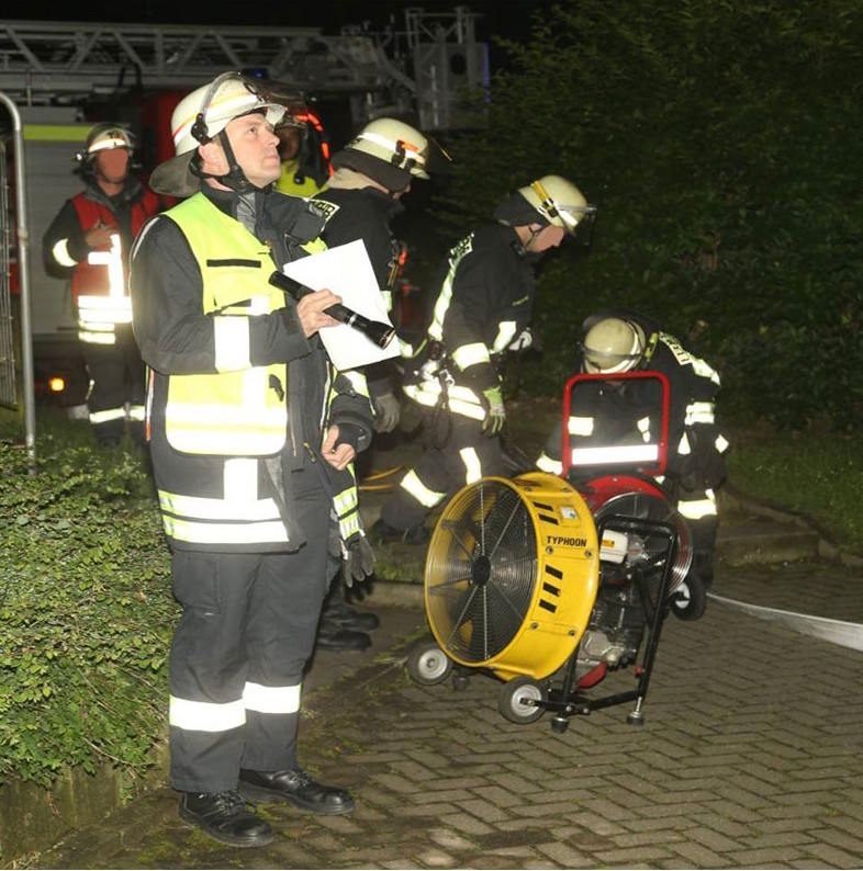 Thorsten Springauf mit weißem Helm und Unterlagen an einer Einsatzstelle bei Nacht