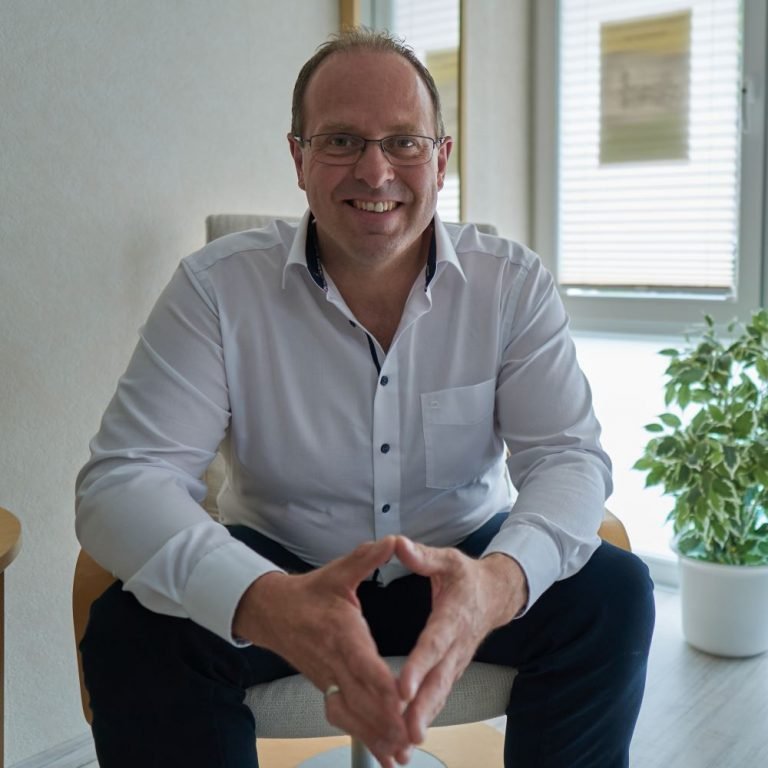 Thorsten Springauf sitzt lächelnd in seiner Coaching-Praxis